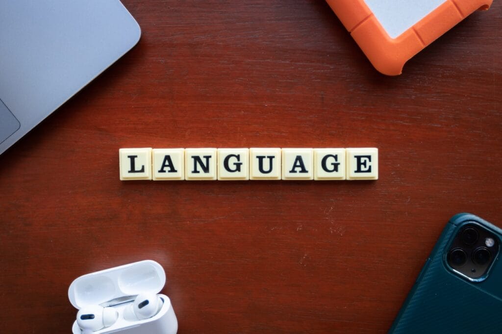 The Scrabble letters make up the word "LANGUAGE" on a red table with some other objects