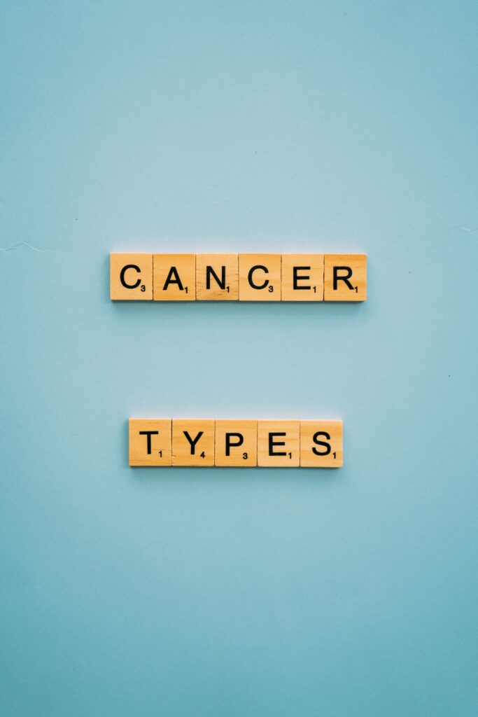 Close-up of wooden tiles spelling 'cancer types' on blue backdrop.